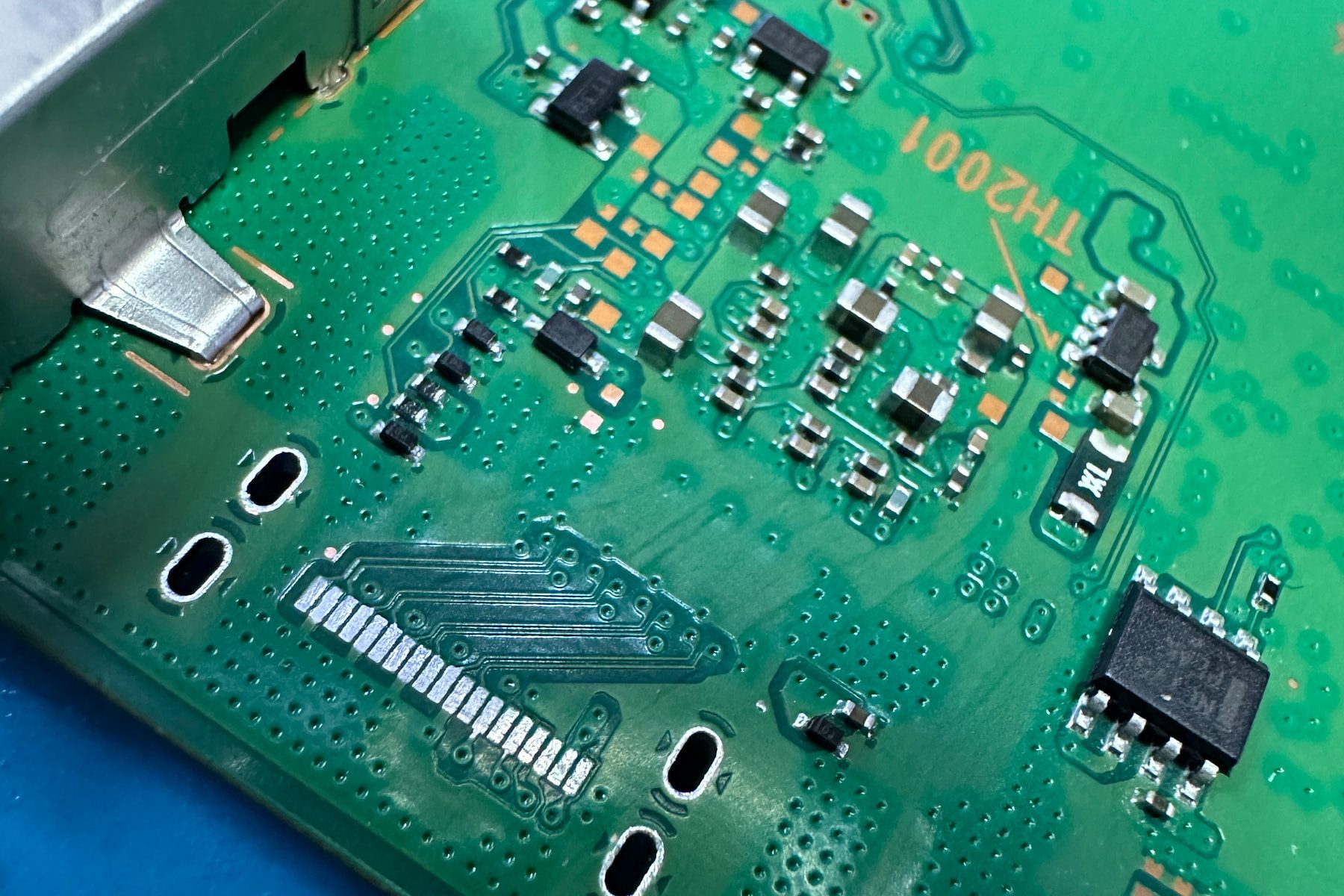Close-up of a circuit board around a removed port and nearby surface-mounted components